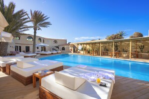 Un espace aménagé au bord de la piscine, avec des chaises longues et une terrasse en bois.