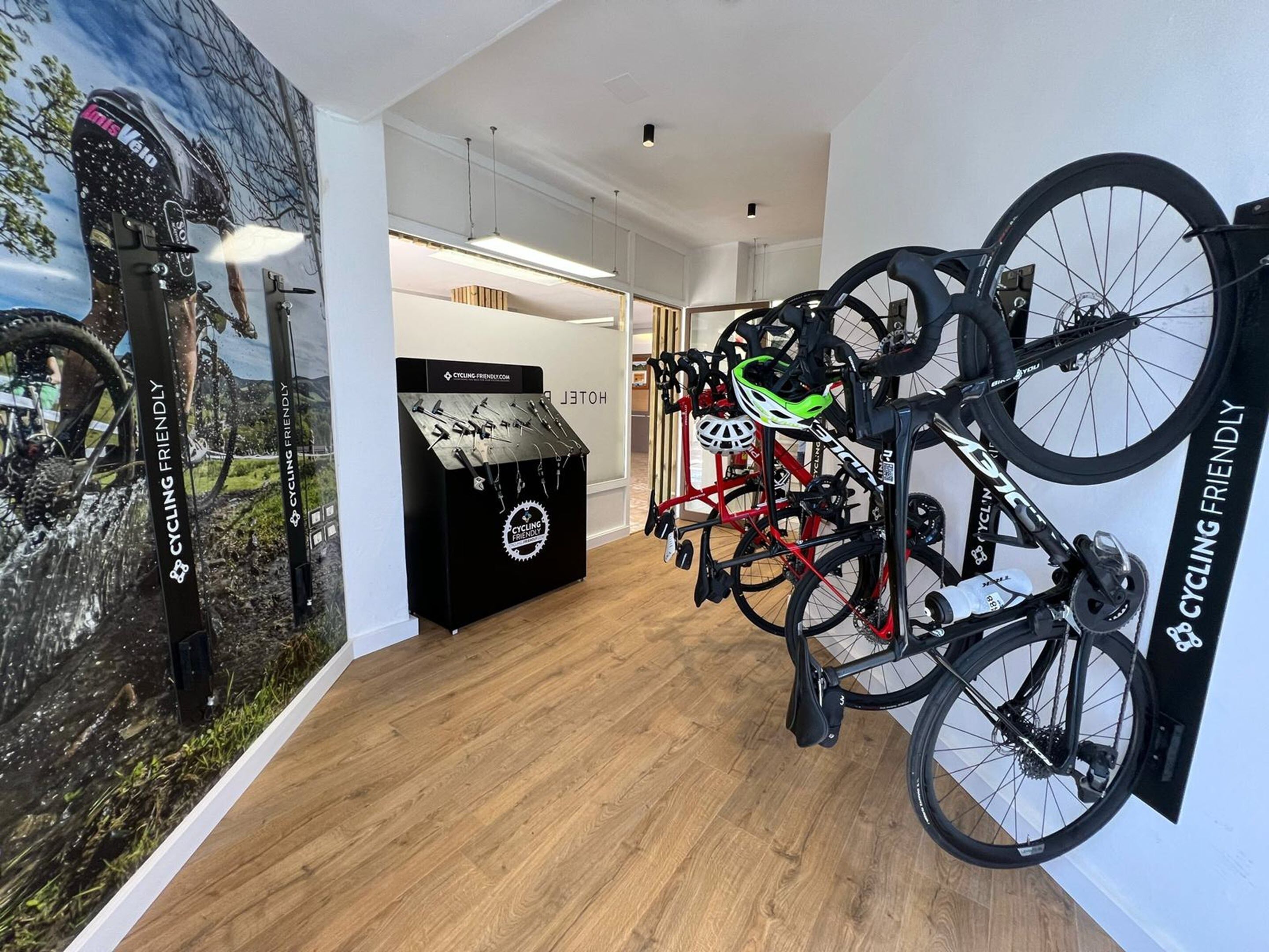 A hotel interior with a cycling-themed wall, a bike rack, and a cycling-friendly sign.
