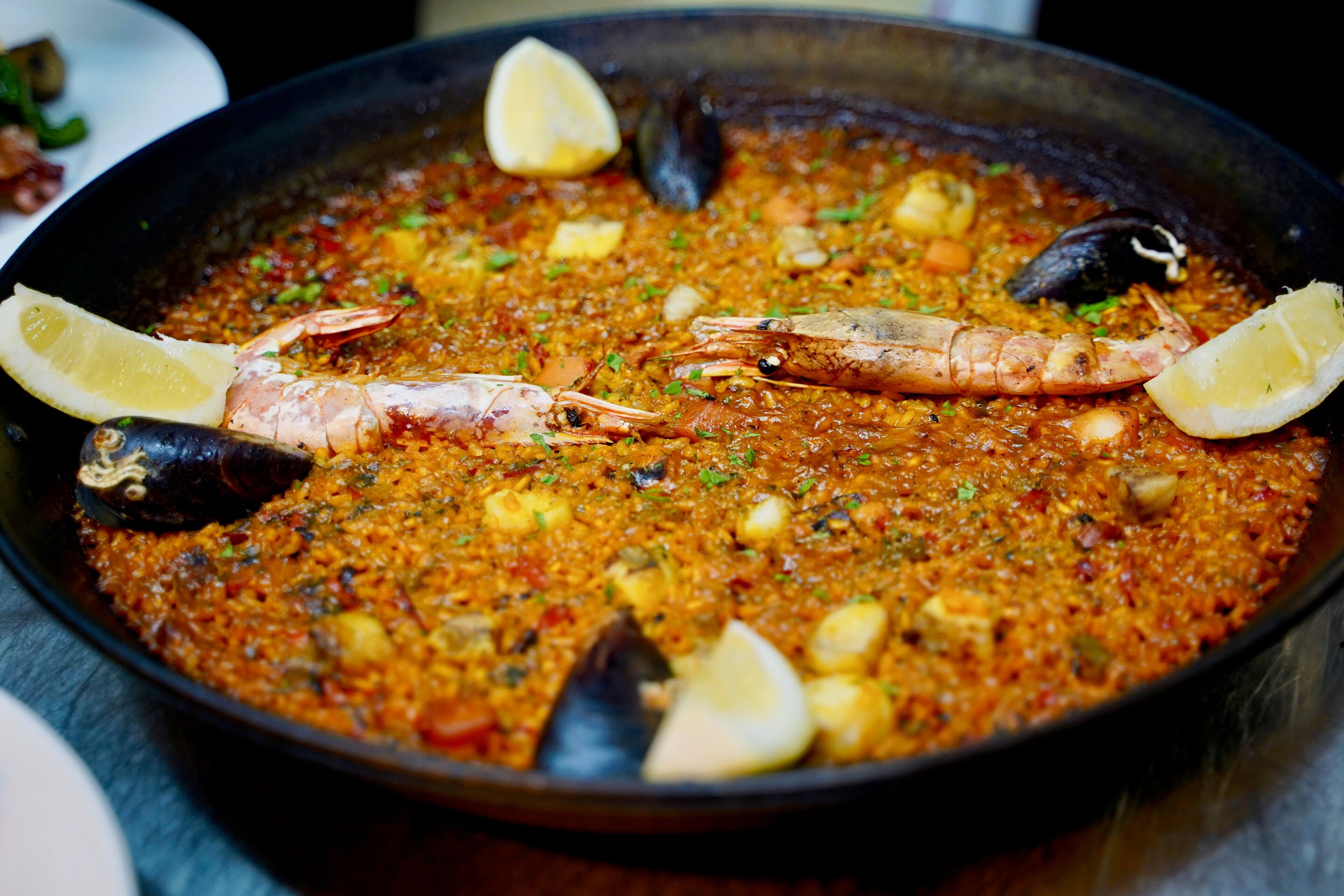 Une paella aux fruits de mer, avec des crevettes et des moules, garnie de tranches de citron.