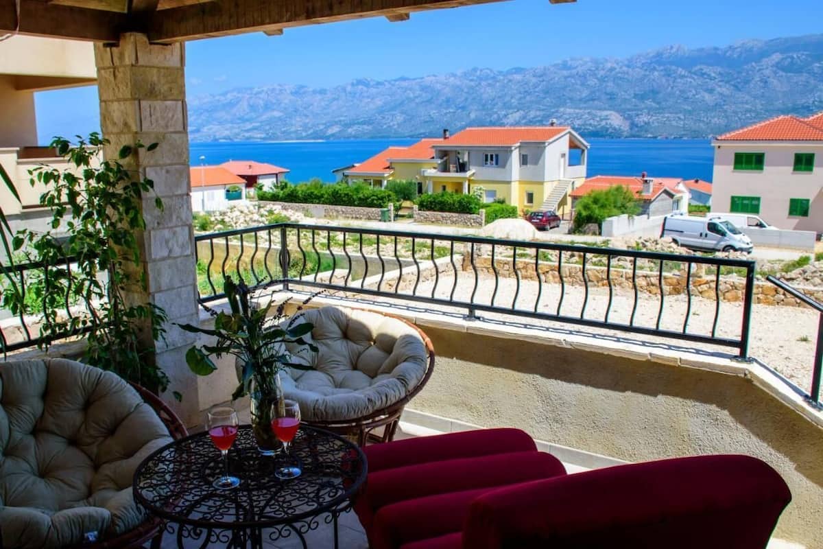 Ein Balkon mit Meerblick, einem Tisch mit Stühlen und einem Blumentopf.
