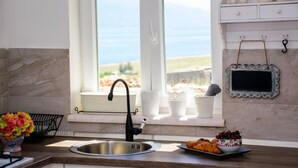 A kitchen with a stainless steel sink, a window with a view of the sea, and a decorative chalkboard on the wall. - Wild Wind Residence (Razanac)