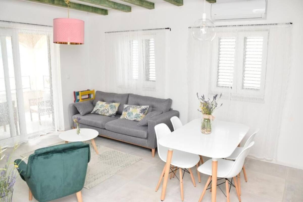 Ein modernes Wohnzimmer mit grauem Sofa, weißem Esstisch und grünem Sessel.