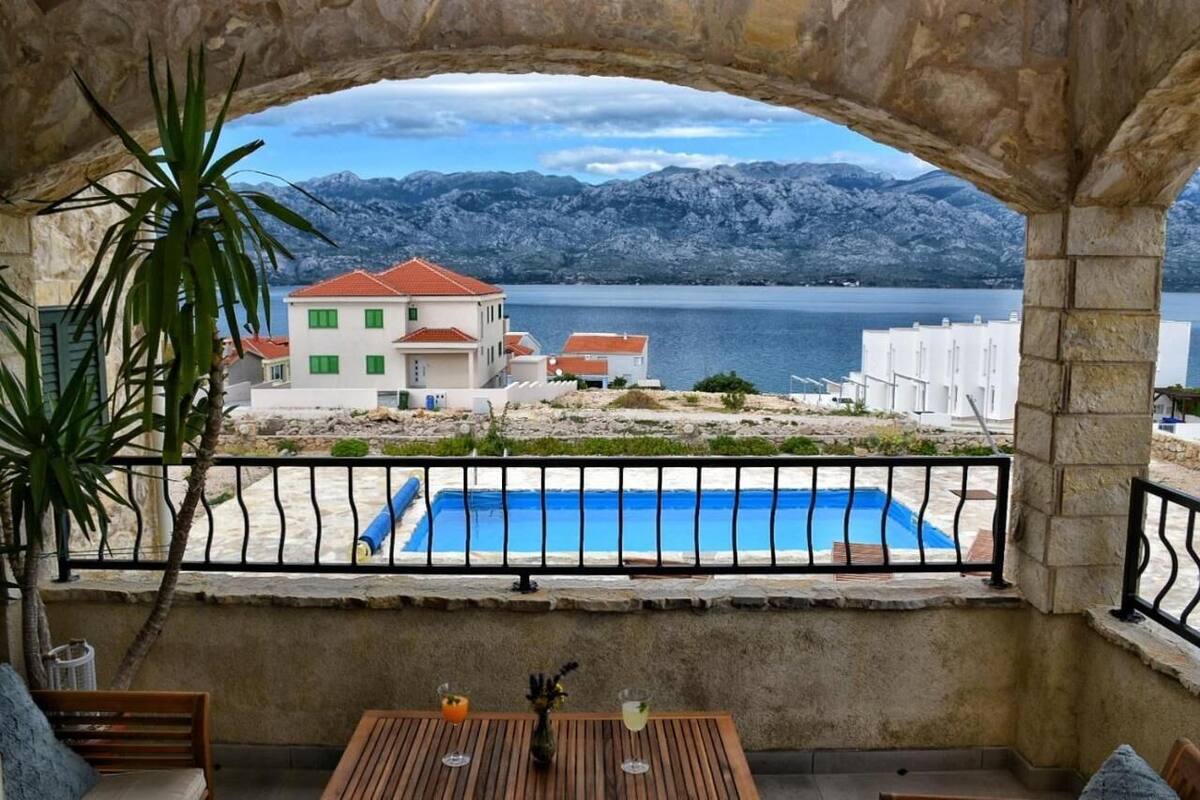 Ein Balkon mit Seeblick und Bergblick, ein Schwimmbad und ein Tisch mit Getränken.