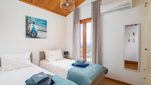 Hotellihuone, jossa on kaksi sänkyä, puinen katto, suuri ikkuna ja ilmastointilaite.