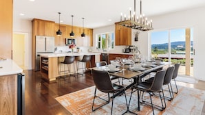 A modern kitchen with wooden cabinets, a central island, and a dining area with a large table and chairs.