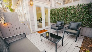A deck with outdoor furniture, a glass-top table, and a white picket fence.