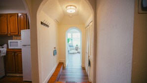 A hallway with an arched ceiling, a white refrigerator, wooden cabinets, and a tiled floor.