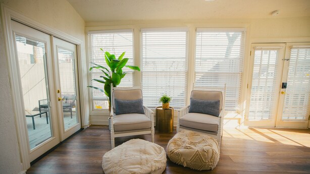 A room with two chairs, a small table, and a potted plant.