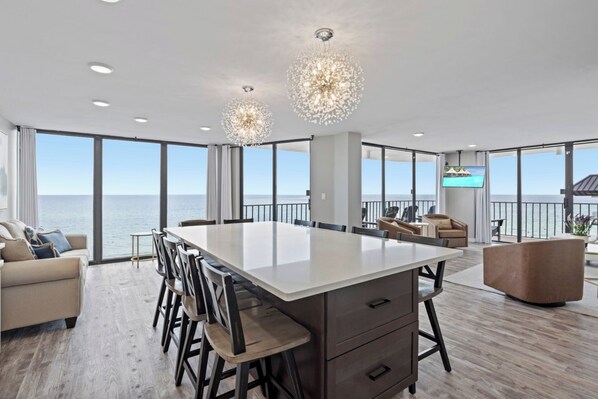 A spacious kitchen with a large island, modern pendant lights, and a view of the ocean. - The Blue Haven offers spacious luxury, beachfront w/stunning wrap-around balcony (Panama City Beach)