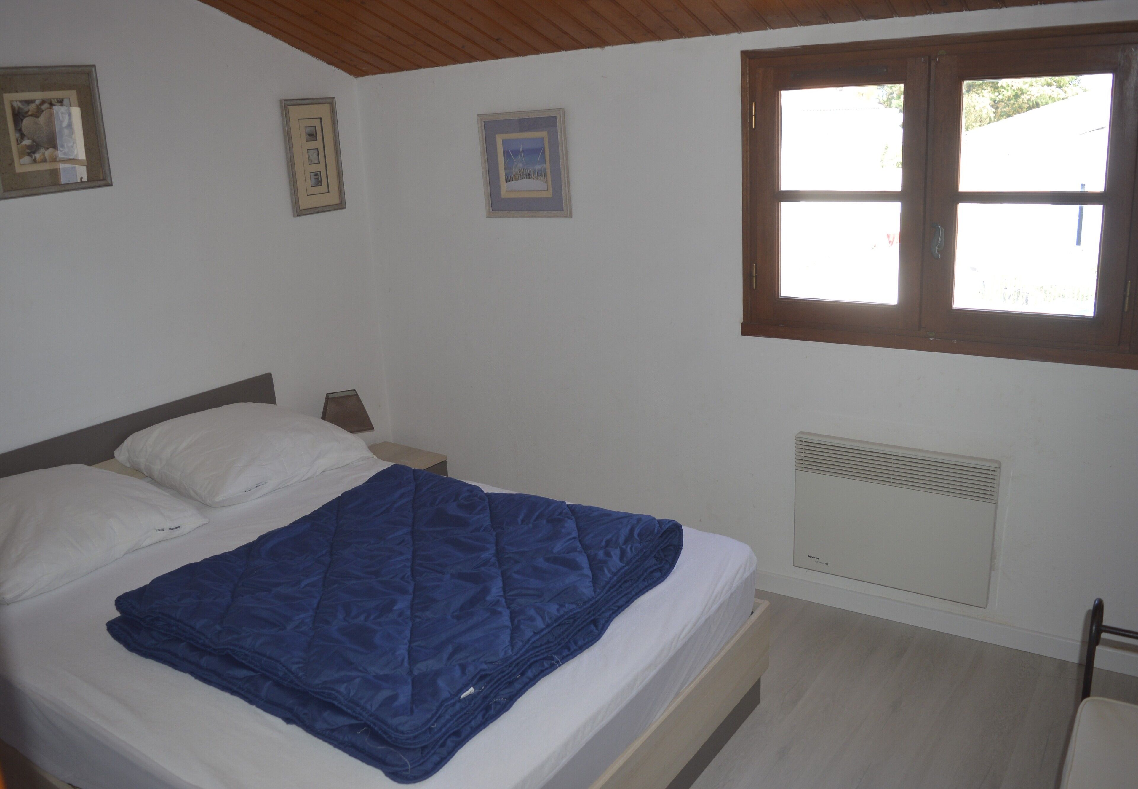 Un dormitorio con cama, ventana y un calentador de pared.