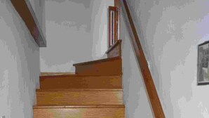 Een houten trap met een leuning, die naar een verdieping leidt.