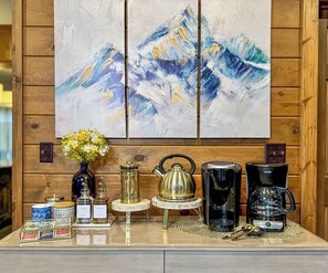 Enjoy a perfectly organized coffee station with a coffee maker, kettle, and coffee pot, along with creamer and sugar.