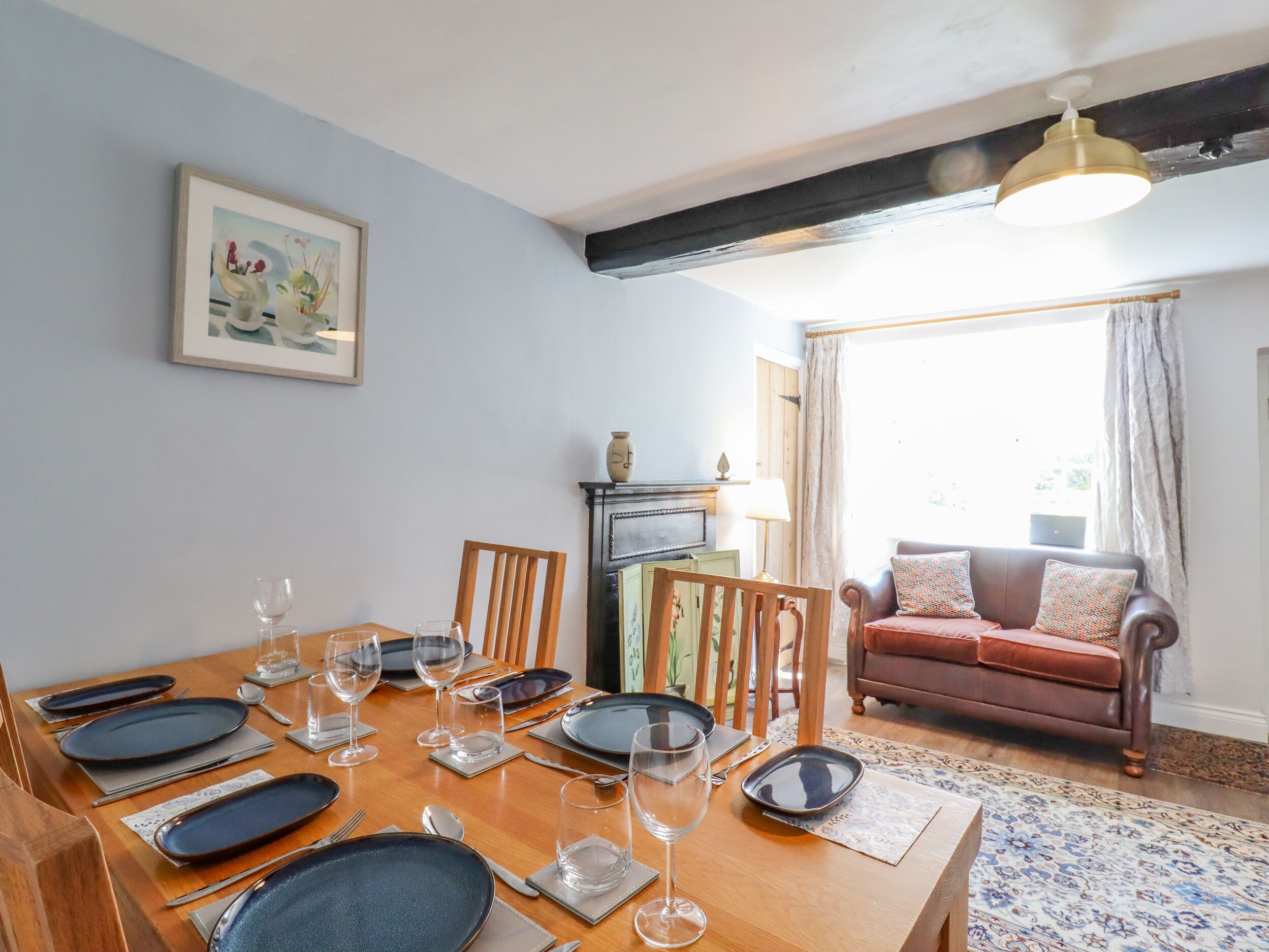 A dining area with a wooden table set for six, a sofa, and a fireplace.