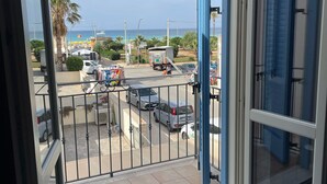 Ein Balkon mit Blick auf einen Parkplatz, eine Straße und das Meer.