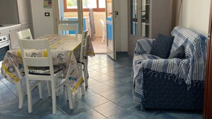 Ein Essbereich mit Tisch und Stühlen, einer Couch und einer Küche im Hintergrund.