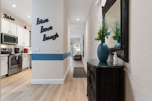 Een moderne keuken met witte kasten, een magnetron en een zwarte oven. Op de blauw-witte wand staat 'Live Love Laugh' geschreven.
