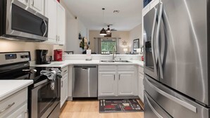 A modern kitchen with stainless steel appliances, white cabinetry, and a central island.