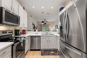 A modern kitchen with stainless steel appliances, white cabinetry, and a central island. - Newly renovated beautiful second floor condo in Bahama Bay (Davenport)