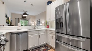 A modern kitchen with stainless steel appliances, white cabinetry, and a dishwasher.
