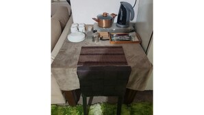 Une petite cuisine équipée d’une cuisinière, d’une bouilloire et de divers ustensiles de cuisine, le tout disposé sur une table.