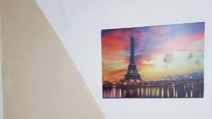 Un mur orné d’un tableau représentant la Tour Eiffel au coucher du soleil.