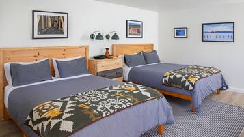 Ein Hotelzimmer mit zwei Betten, einem Holzkopfteil, einem Nachttisch, einer Lampe und gerahmten Bildern an der Wand.