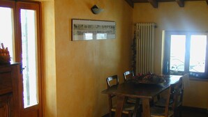 A dining area with a wooden table and chairs, a framed picture on the wall, and a window with curtains. - Attic with lake view (Campodolcino)