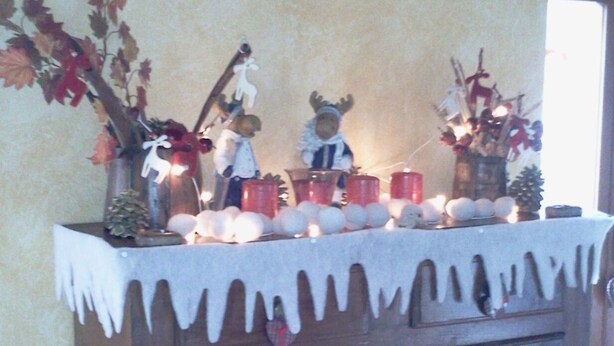 A wooden cabinet with a white draped cloth, decorated with small figurines, candles, and a pine cone. - Attic with lake view (Campodolcino)