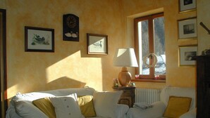 A room with two white sofas with yellow cushions, a wooden side table with a lamp, and framed pictures on the wall. - Attic with lake view (Campodolcino)