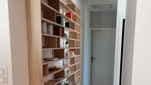 A hallway with a wooden shelving unit filled with various items, leading to a door at the end. - Recent villa with air conditioning and private pool on the heights of Barjac (Barjac)