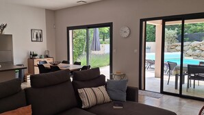 A modern living room with a sofa, a dining table, and a kitchen area with a refrigerator. - Recent villa with air conditioning and private pool on the heights of Barjac (Barjac)