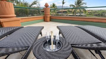 A balcony with wicker furniture, a bottle of champagne, and glasses.