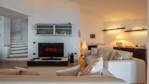 Een moderne woonkamer met een flatscreen televisie, een open haard en een trap.