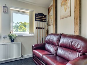 A room with a red leather sofa, a window with a view of trees, a radiator, and a wall-mounted clock. - Greystones Nawab Annex C (Flagg, Buxton)