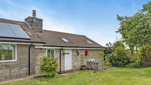 Une maison en pierre avec un panneau solaire, une porte blanche et une boîte aux lettres.