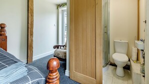 Une chambre à coucher comprenant un lit, une armoire en bois, une porte coulissante, une salle de bain avec des toilettes et une douche.