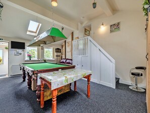 A pool table with a green felt surface, a wooden bench with a floral tablecloth, and a white staircase with a railing. - Greystones Nawab Annex C (Flagg, Buxton)