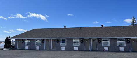 A motel with a row of rooms, each with a door and a window.