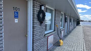 Un edificio de fachada de ladrillo, número 101, con entrada accesible para personas con discapacidad, ventanas decoradas con coronas y un camino pavimentado.