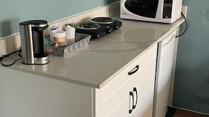 Une petite cuisine équipée d’une machine à café, d’un four à micro-ondes et d’une petite cuisinière.
