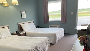 Une chambre d’hôtel avec deux lits, un bureau et une fenêtre avec des rideaux.