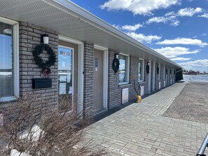 A row of hotel rooms with brick walls, wreaths, and a snow-covered ground. - Earlton Motel (Armstrong)