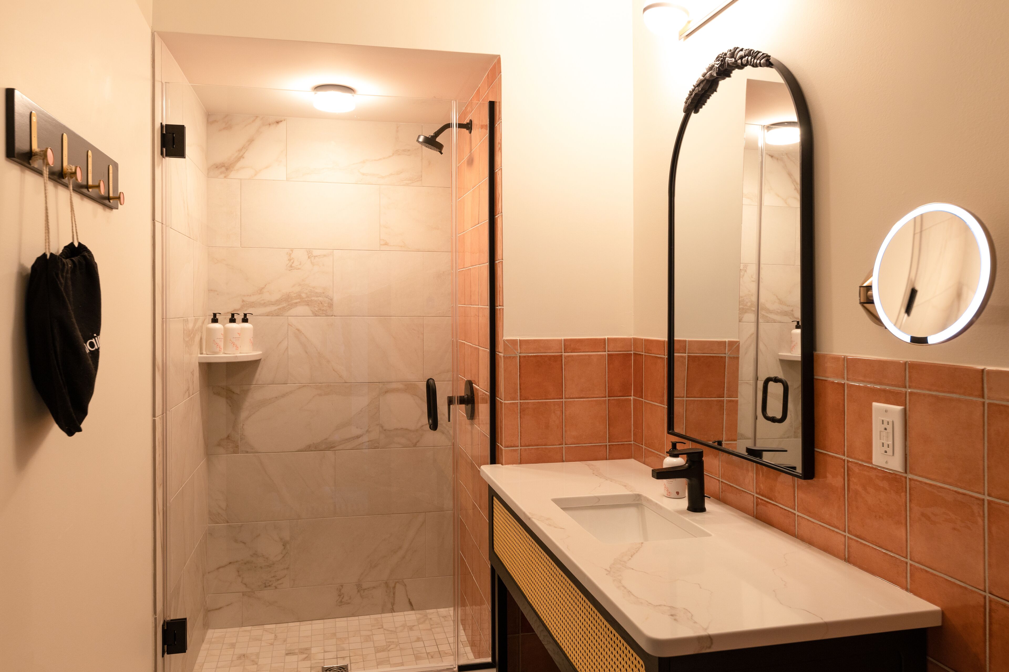 A bathroom with a shower, a sink, a mirror, and a towel rack.
