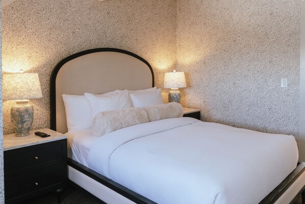 A neatly made bed with white linens, a headboard, and two bedside lamps on a nightstand. - Hotel Thaxter (Portsmouth)