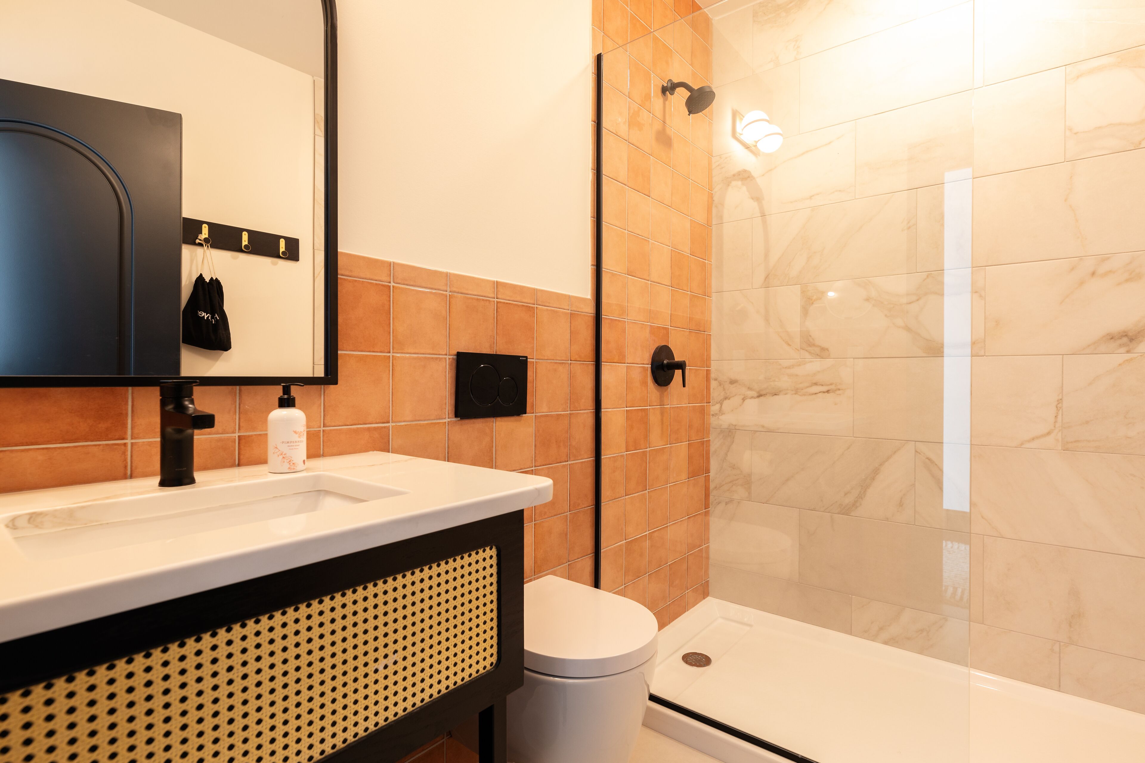 A modern bathroom with a sink, mirror, and shower.