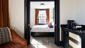 A hotel room with a bed, a desk with a coffee maker, and a view of the outside through a window with curtains. - Hotel Thaxter (Portsmouth)