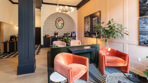 A modern interior with a checkered floor, a desk, two orange chairs, a green sofa, and a large plant. - Hotel Thaxter (Portsmouth)