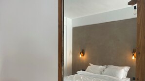 A bedroom with a bed, wooden headboard, and two wall-mounted light fixtures. - Rustic Hill Private Pool Rooms (Kalamata)