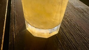 A glass of cocktail with mint leaves and a lime wedge on a wooden table by a body of water during sunset. - Rustic Hill Private Pool Rooms (Kalamata)