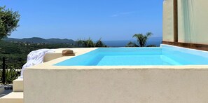 A rectangular pool with a clear blue water surface, surrounded by a beige wall. - Rustic Hill Private Pool Rooms (Kalamata)
